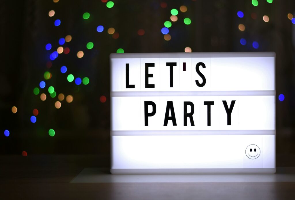Illuminated lightbox with 'Let's Party' message, surrounded by colorful bokeh lights.