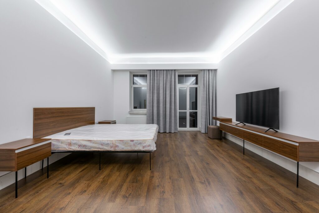 Spacious, minimalist bedroom with a wooden floor and modern design elements.