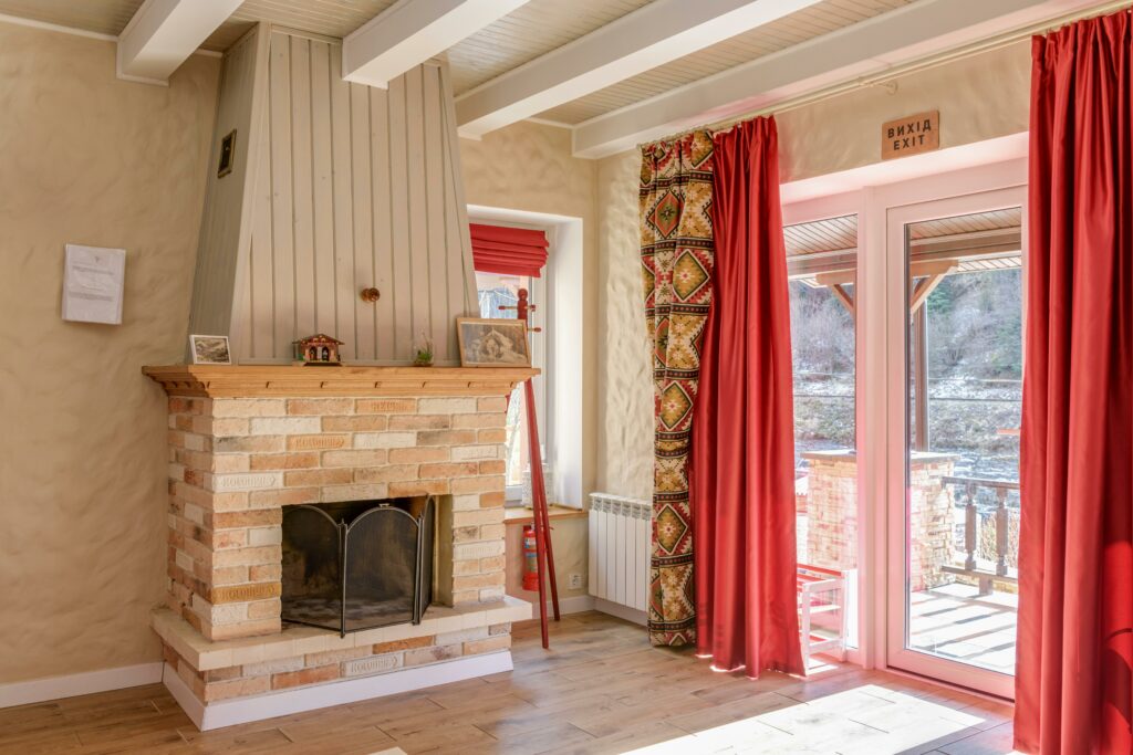 Inviting interior with a brick fireplace and red curtains, featuring elegant decor.